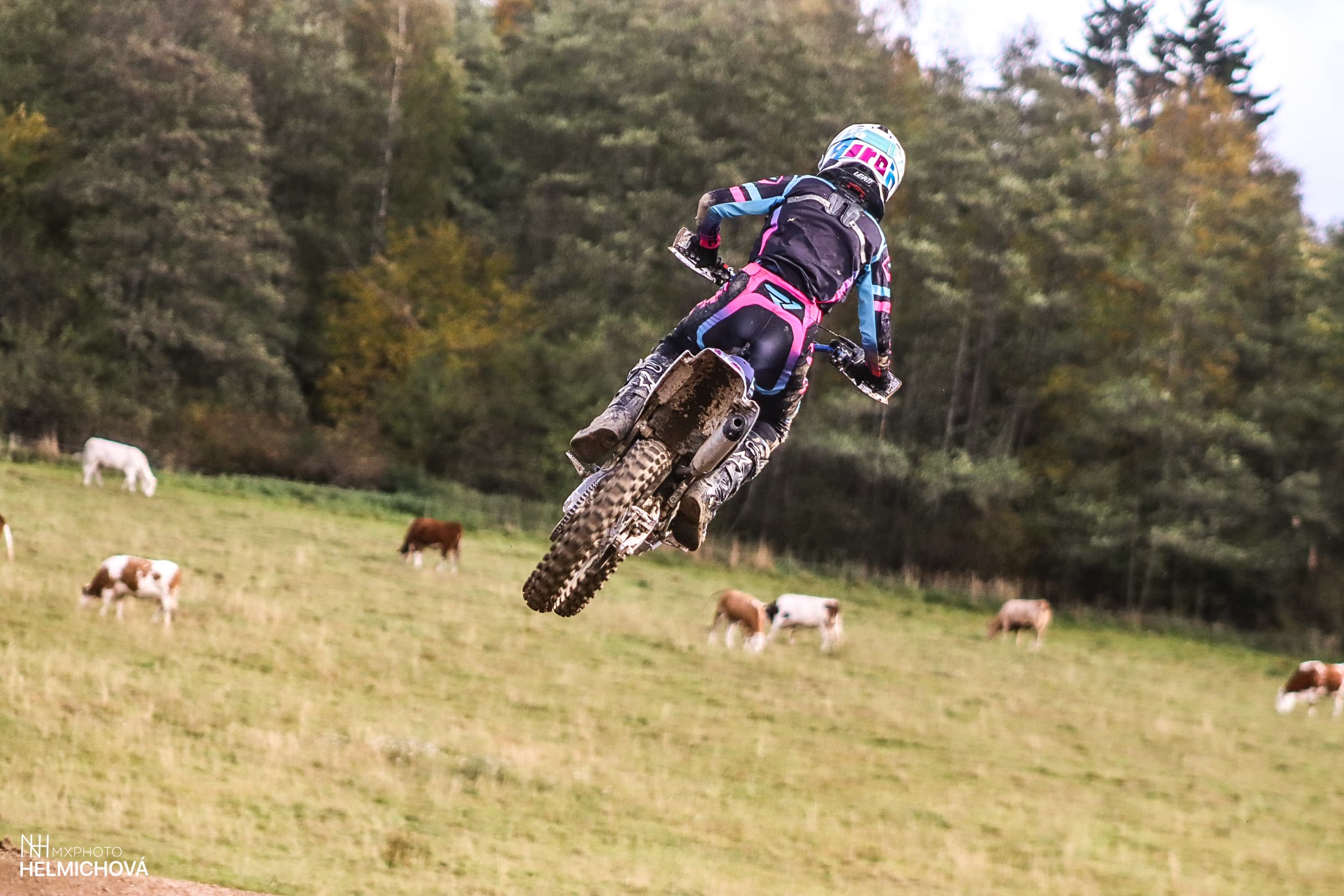 Motokrosový závodník ve vzduchu nad pastvinami